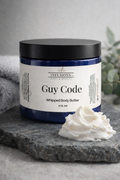Jar of 'Guy Code' whipped body butter with a dollop on a stone surface.